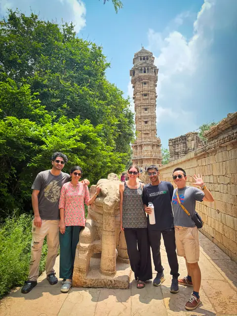 A small group on a fort path below a tall carved stone tower