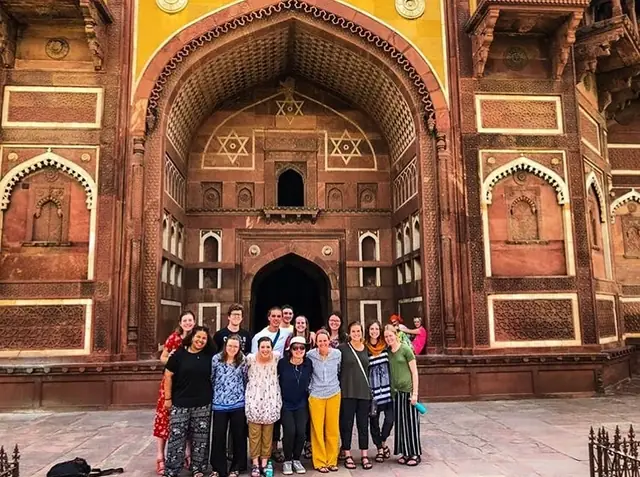 A group gathered in front of a tall sandstone gateway with inlaid stonework