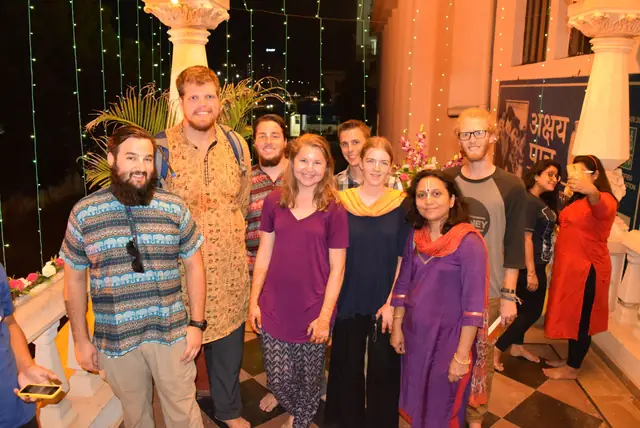 A group of guests together outdoors on a festival evening, under strings of lights