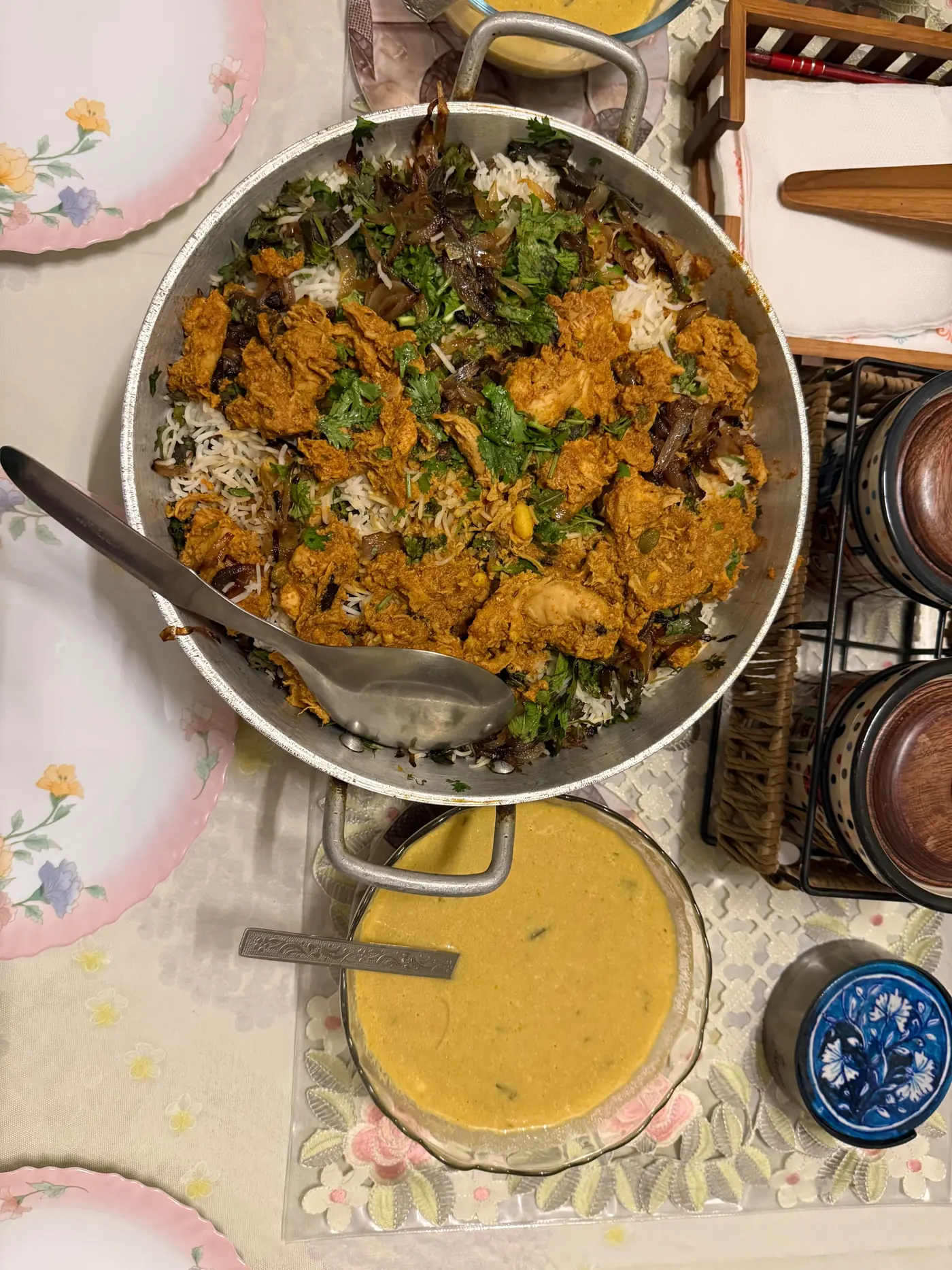 A pan of home-made biryani and a bowl of curry set out on a family table
