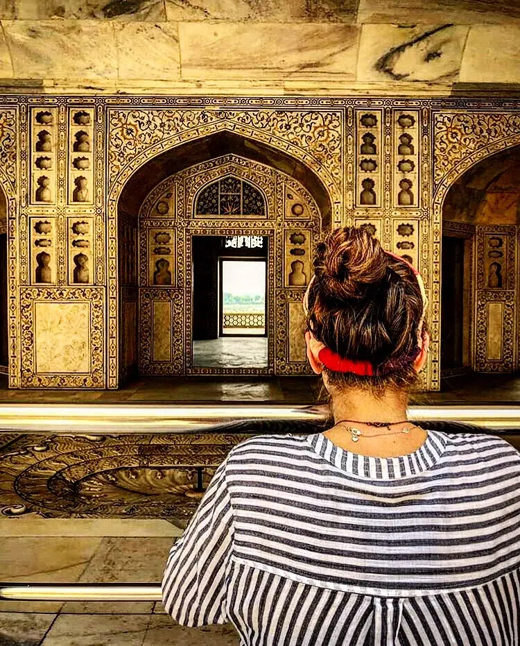A traveller sitting before a gilded and mirrored Mughal interior at Agra Fort