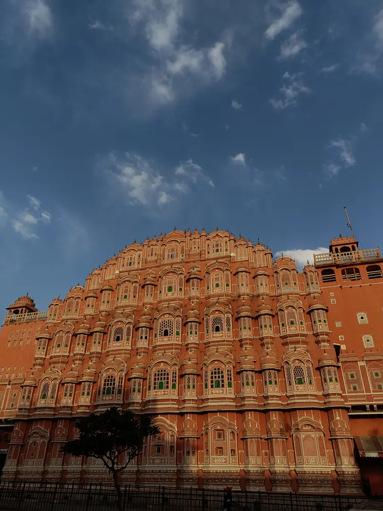 The tiered pink facade of Hawa Mahal in Jaipur under a dark sky