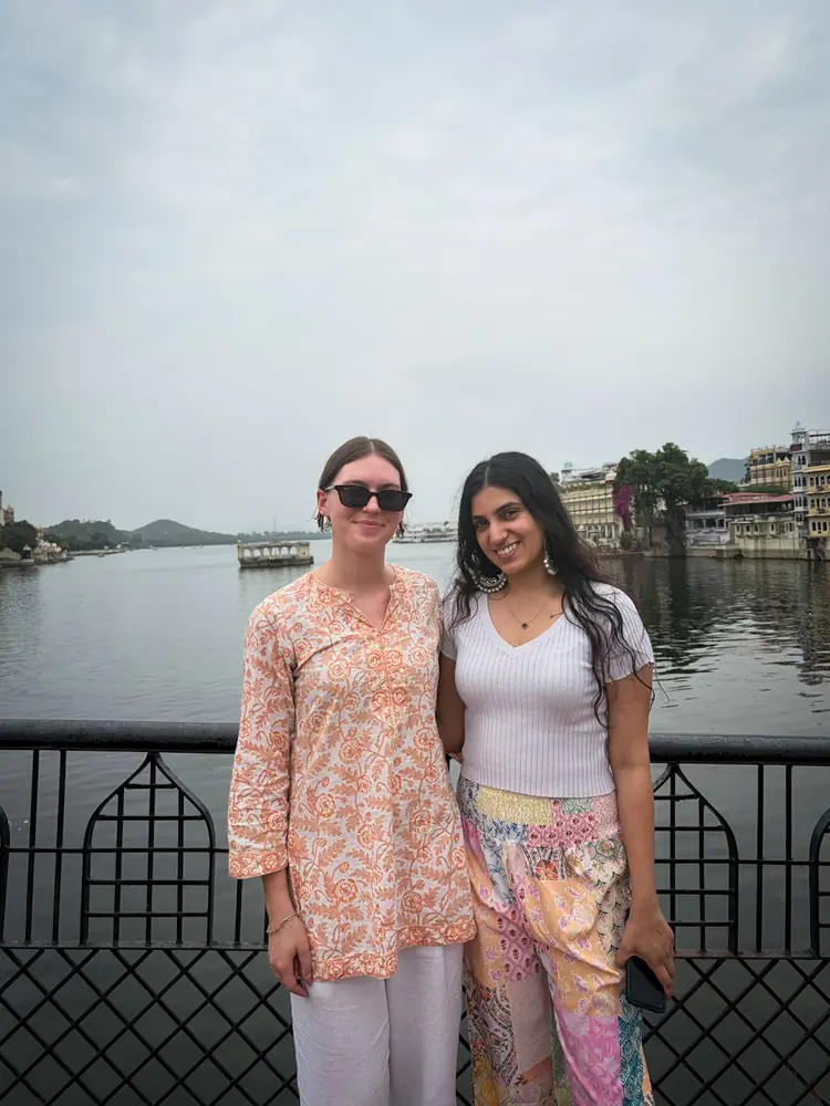 Two travellers at the edge of Lake Pichola with the old city behind them
