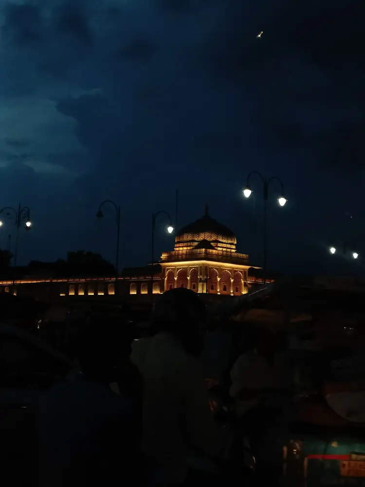 A palace gateway lit gold above a crowded street at night