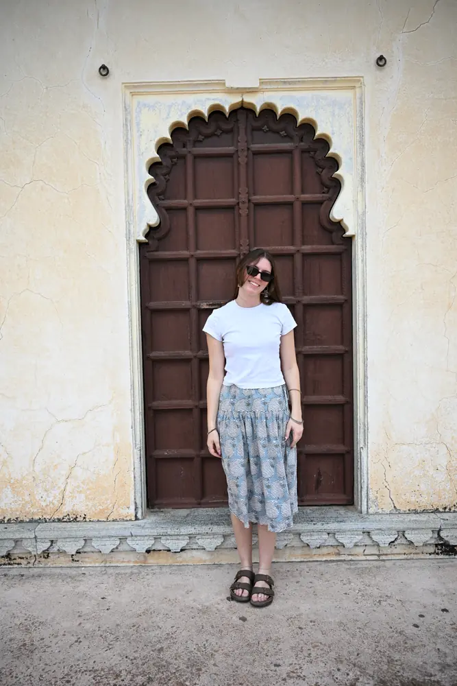 A traveller standing in the scalloped doorway of a pale yellow building