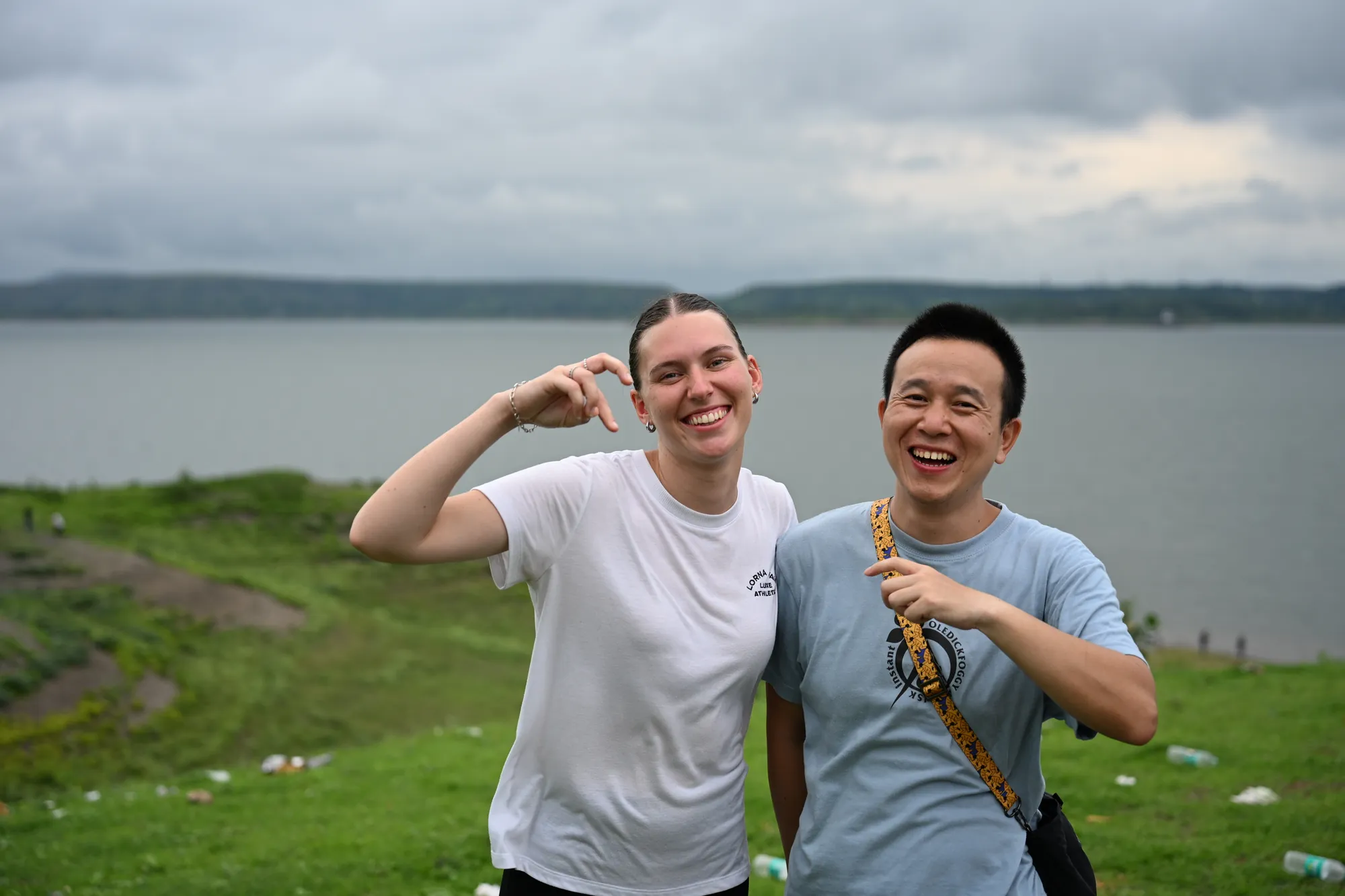 Two travellers laughing beside a lake under monsoon cloud in southern Rajasthan
